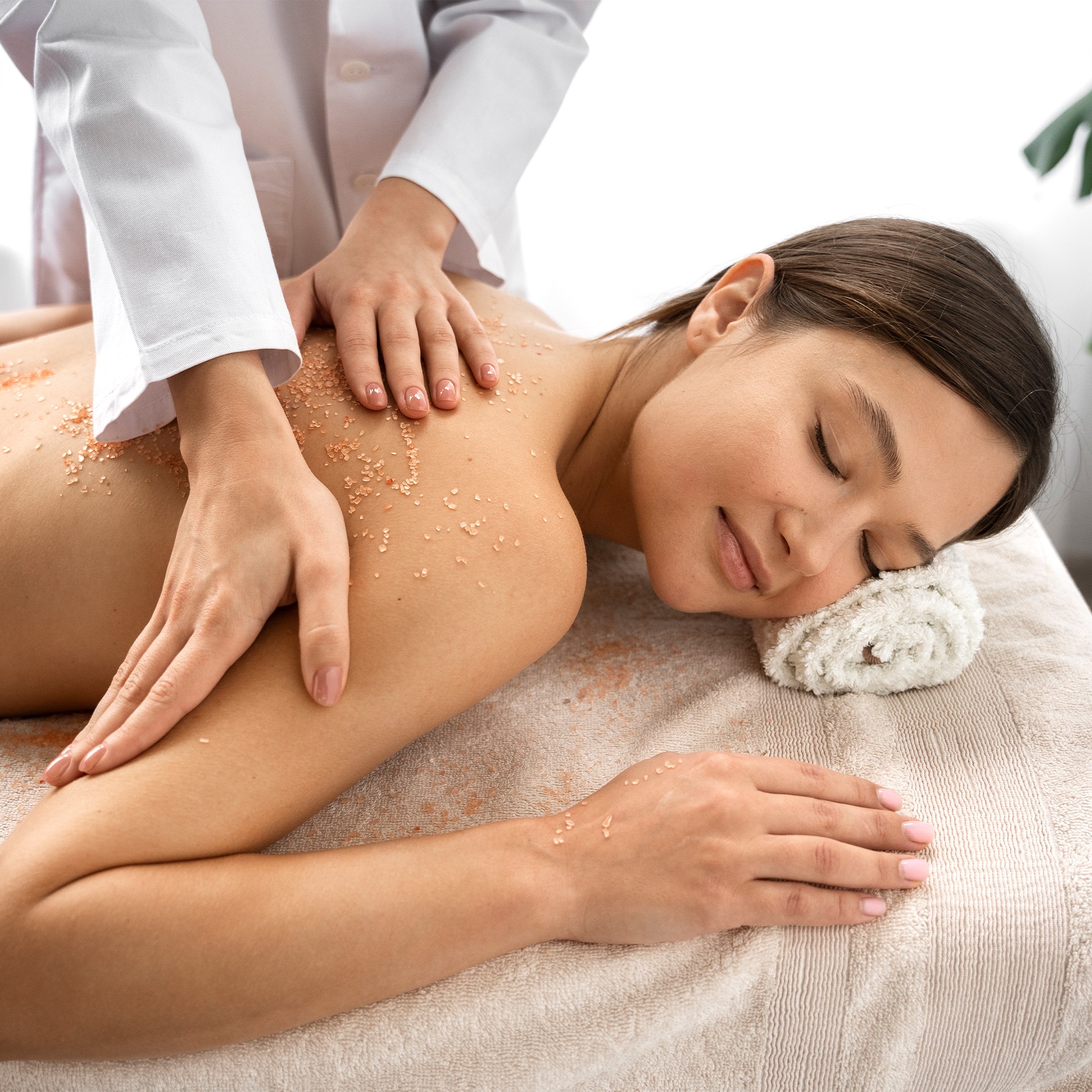 Close-up of a woman with under-eye gel patches, natural makeup, and smooth skin, against a neutral beige background