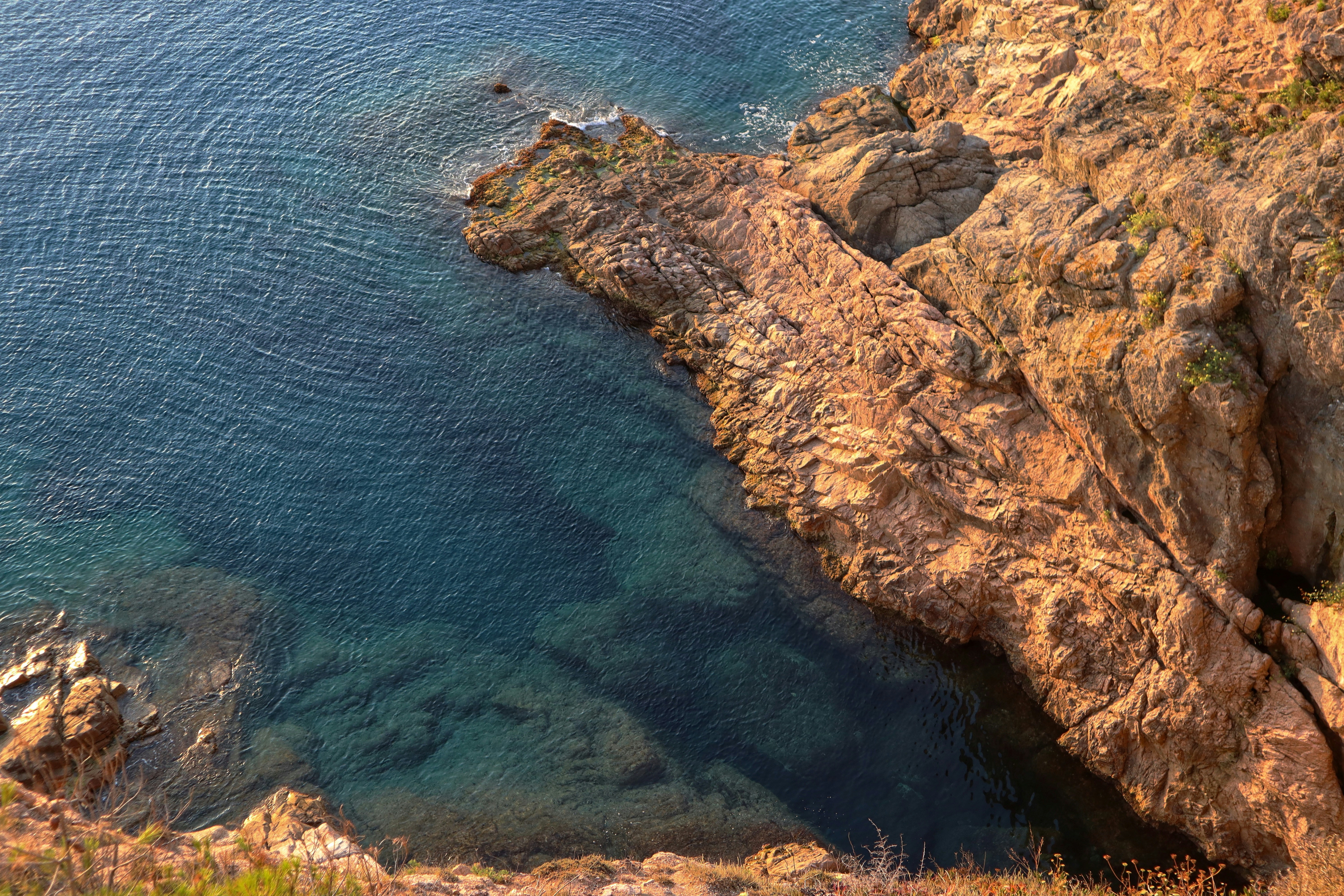 a rocky cliff next to a body of water