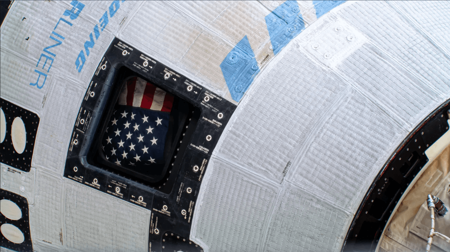 The American flag shown inside the window of Boeing's Starliner spaceship on the International Space Station. Credit: NASA.