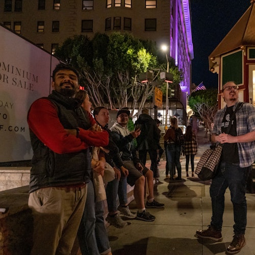Guide telling a story to a group in a busy city square.