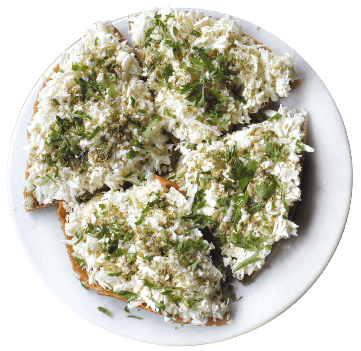 Gourmet dish plated in a black bowl on a dark wooden table.