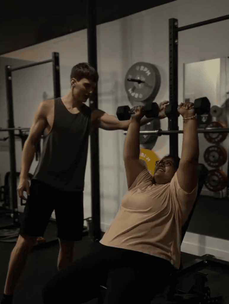 Brady Alexov coaching a client who is lifting weights