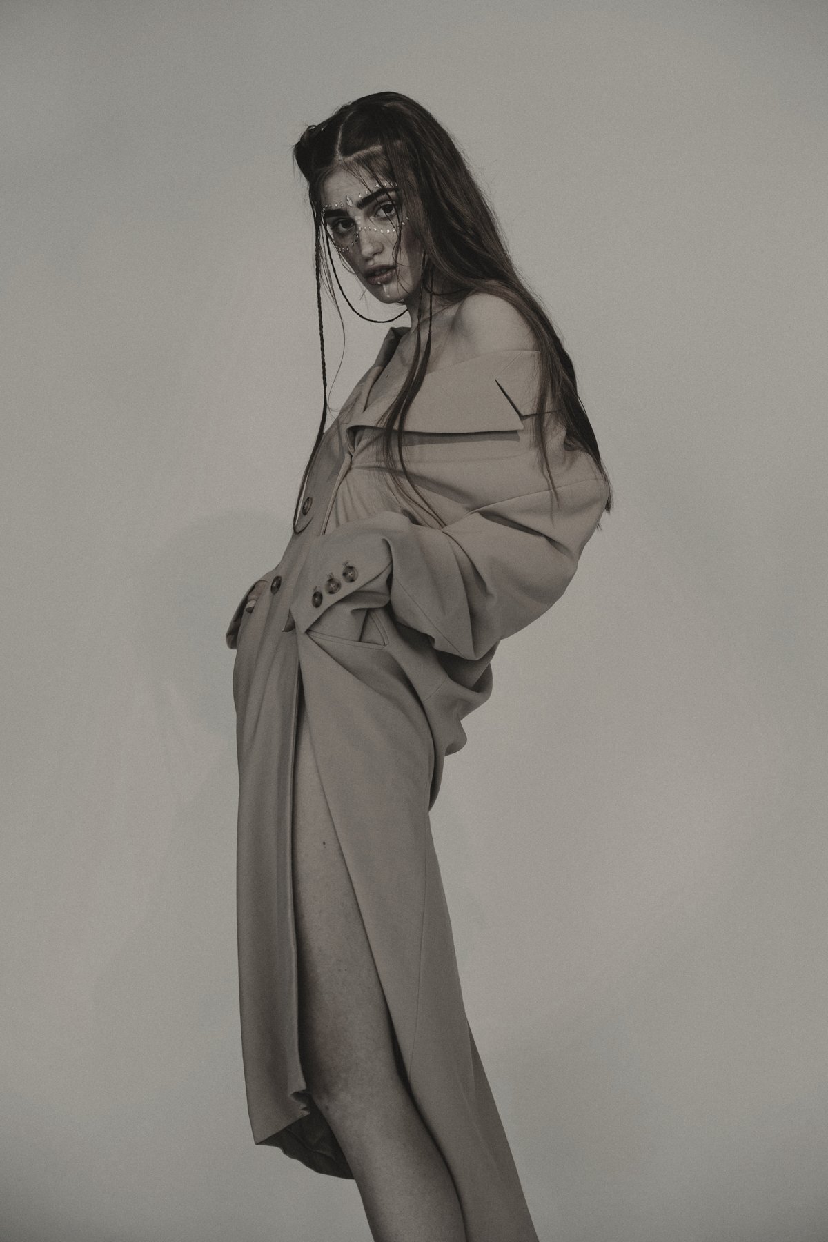 Model in a draped camel trench worn off the shoulder
