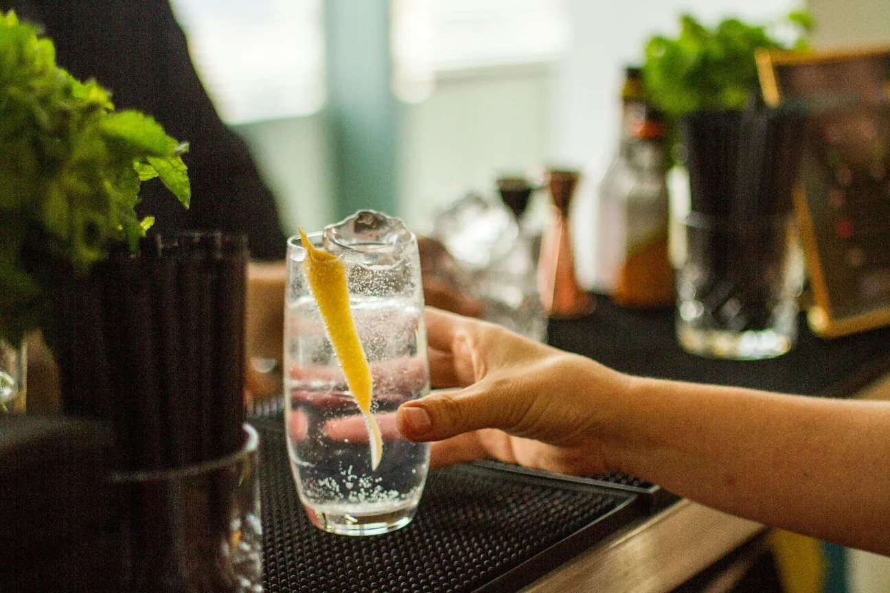 a person holding a lemon in a glass of water