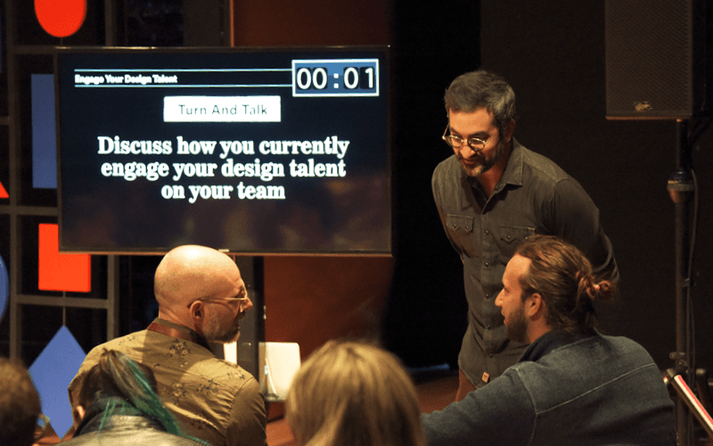 A flat-team environment with practitioners working across a shared surface, side by side.