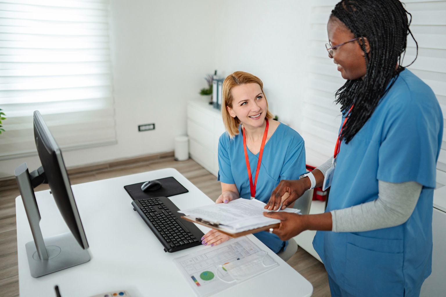 Two healthcare workers reviewing paperwork at a clinic desk