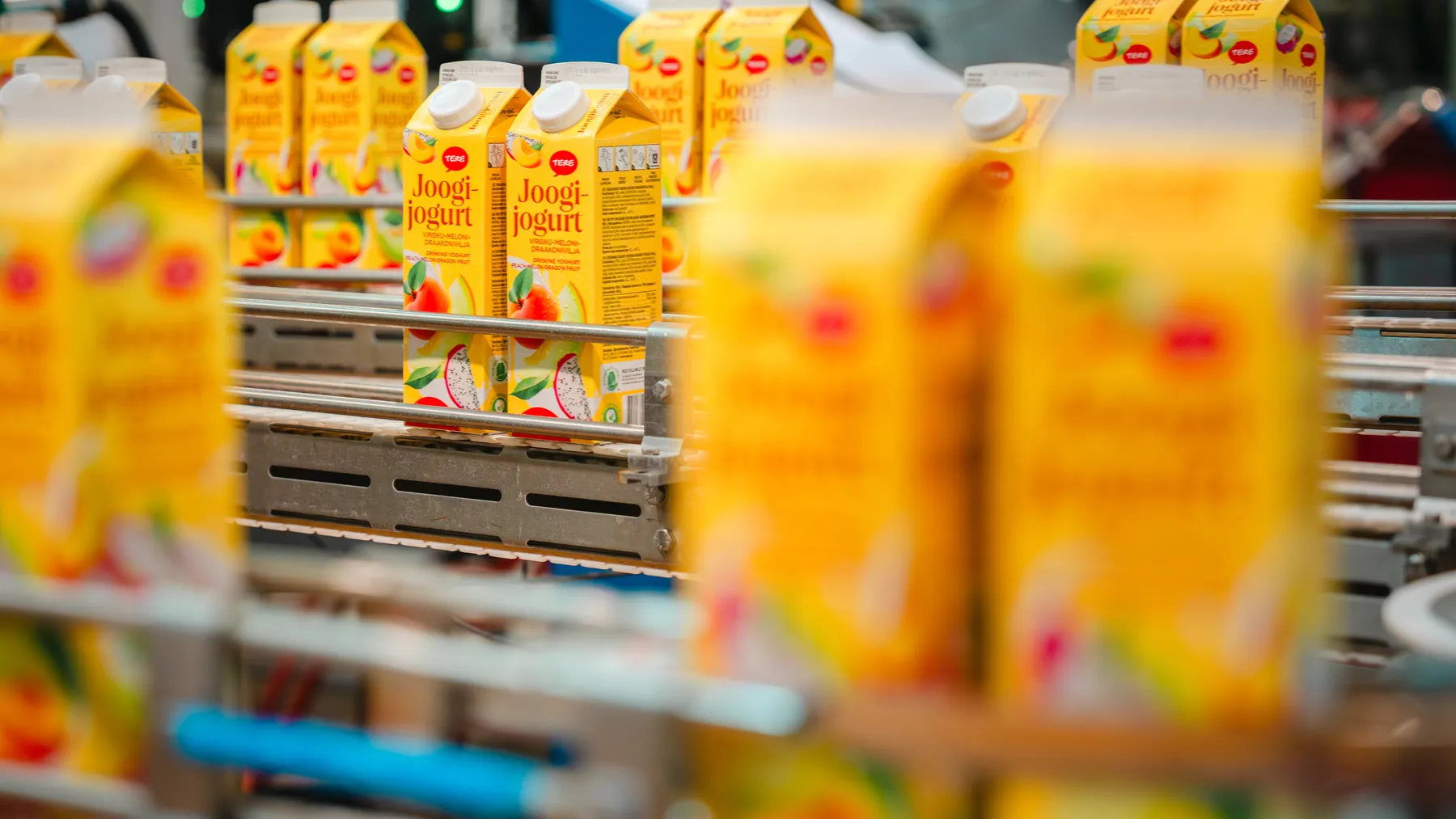 Tere drinking yogurt cartons moving along a factory production line
