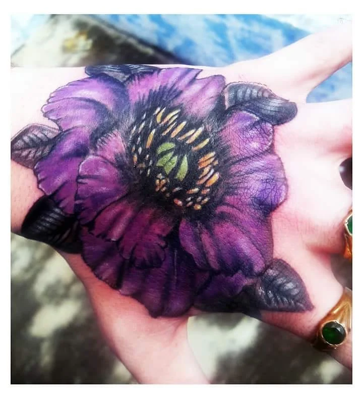 Old fashioned, purple colour ink flower tattoo on hand by a tattoo artist in Bangalore at Fred's tattoo studio, featured among the best tattoo places in Bangalore.