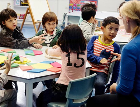 Diverse students and teacher learning with colorful geometric shapes.