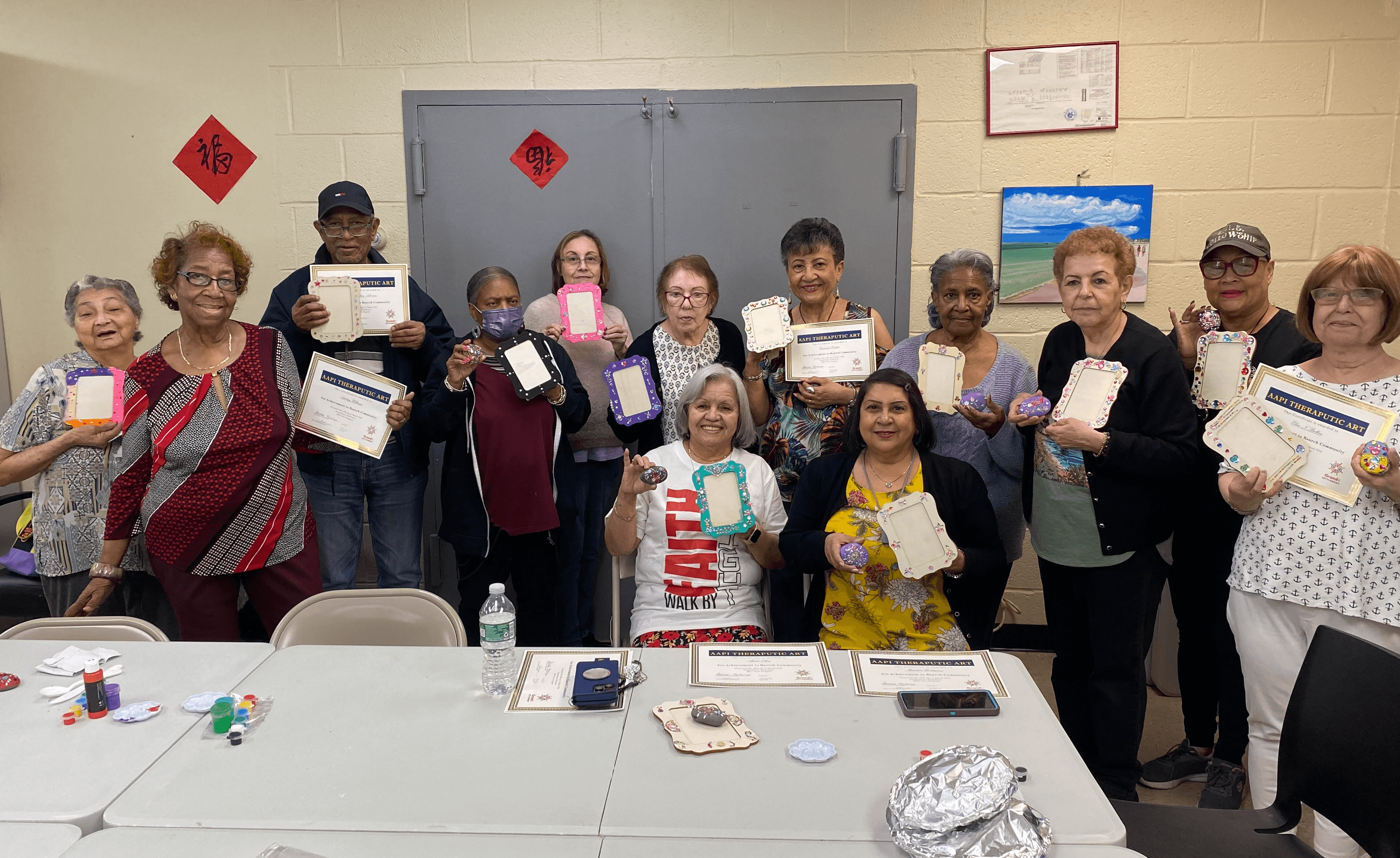 Seniors proudly holding their recent crafts and certificates for Art Therapy.
