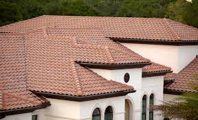 Modern home with red Spanish tile roof and white stucco exterior. Green trees in background.