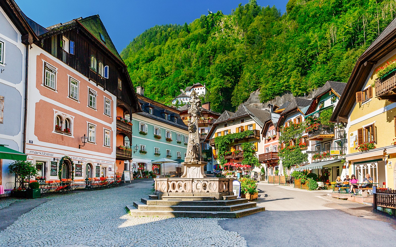Colorful buildings and central fountain in Hallstatt village square, Austria.