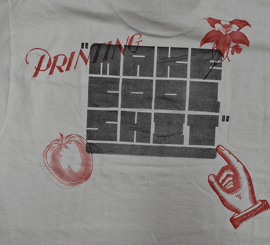 Make Cool Shit block letters printed in black on the back of a white shirt. Four red icons sit in each corner of the design, the word "Printing", a flower, and apple, and a pointing finger.