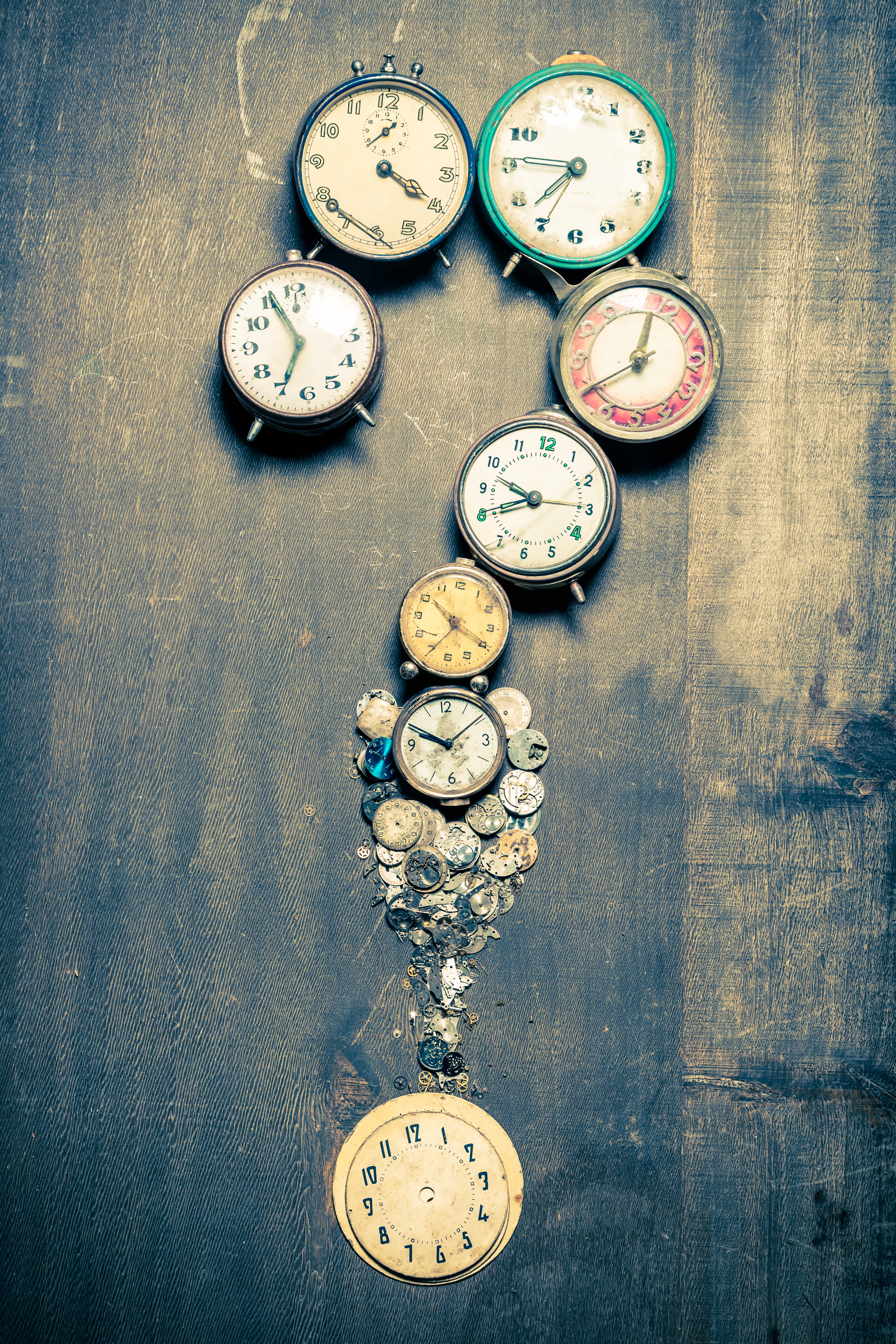 Vintage alarm clocks arranged in the shape of a question mark on a wooden surface, representing the critical timing questions every service business owner needs to answer before committing to a marketing investment
