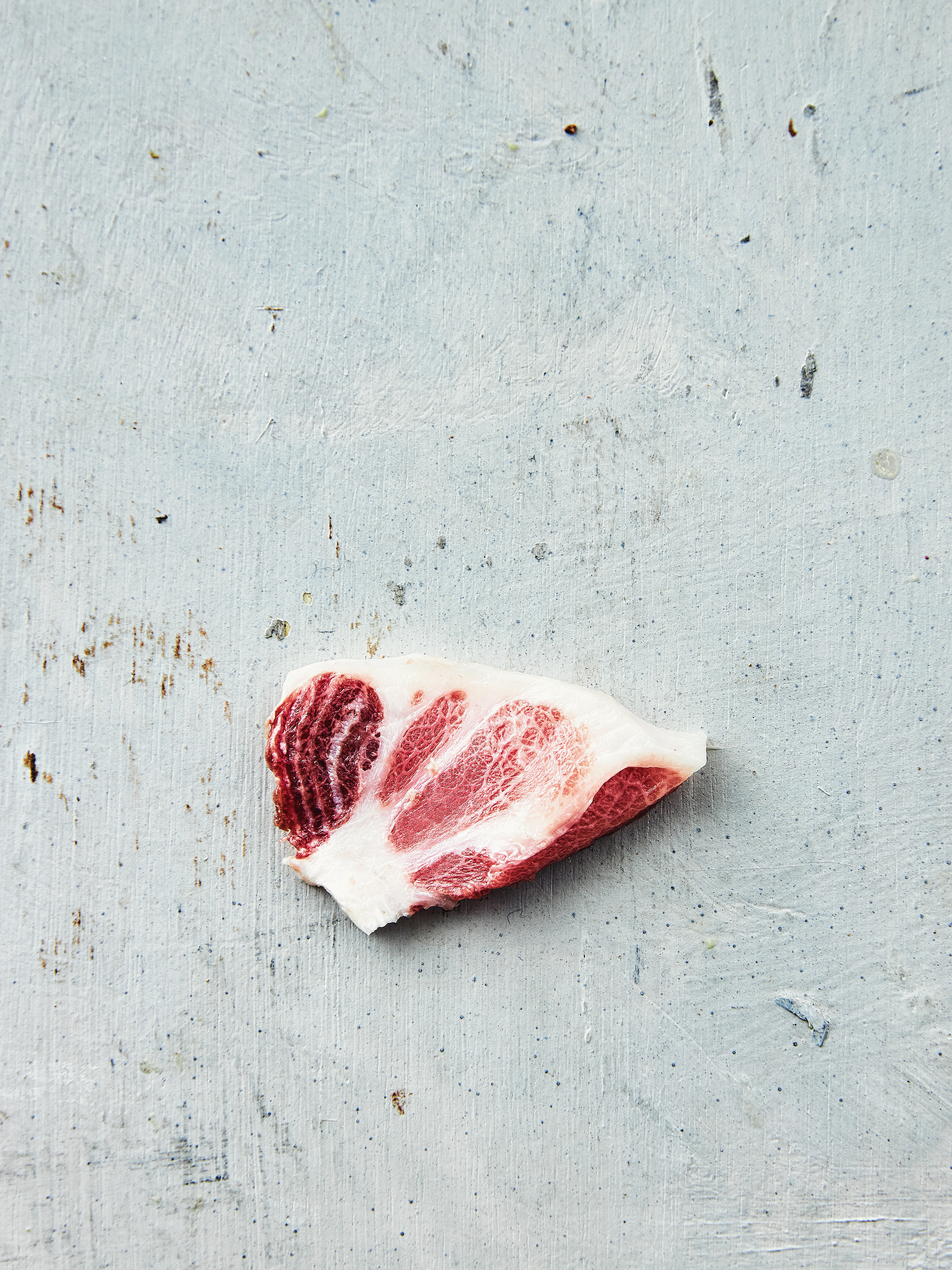 A wooden desk by a window, with sunlight illuminating a laptop, notebook, and a decorative vase.