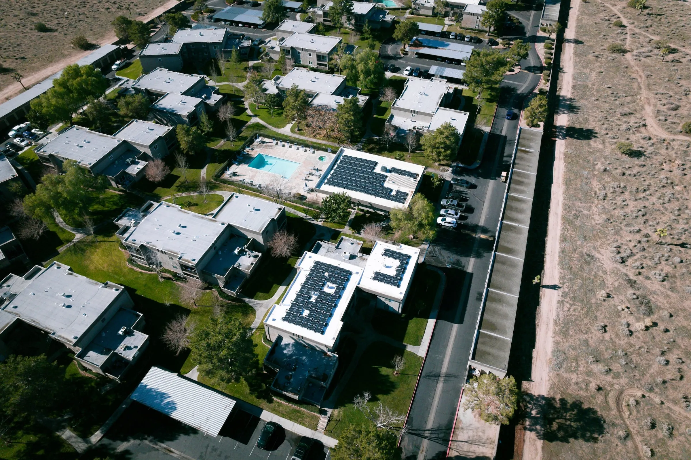 Aerial view of a neighborhood at the edge of the desert with solar panels on several rooftops