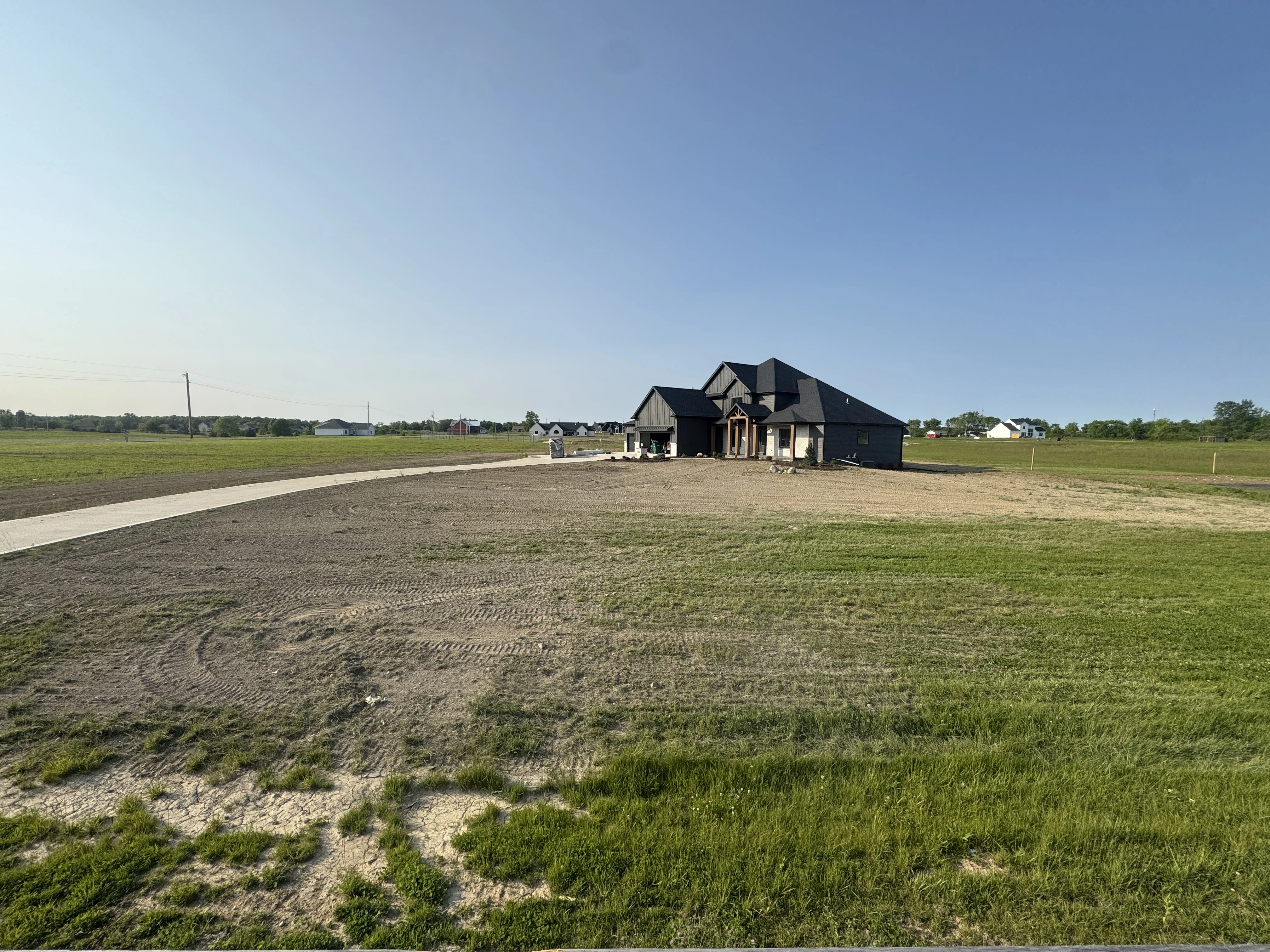 gray asphalt road between green grass field during daytime
