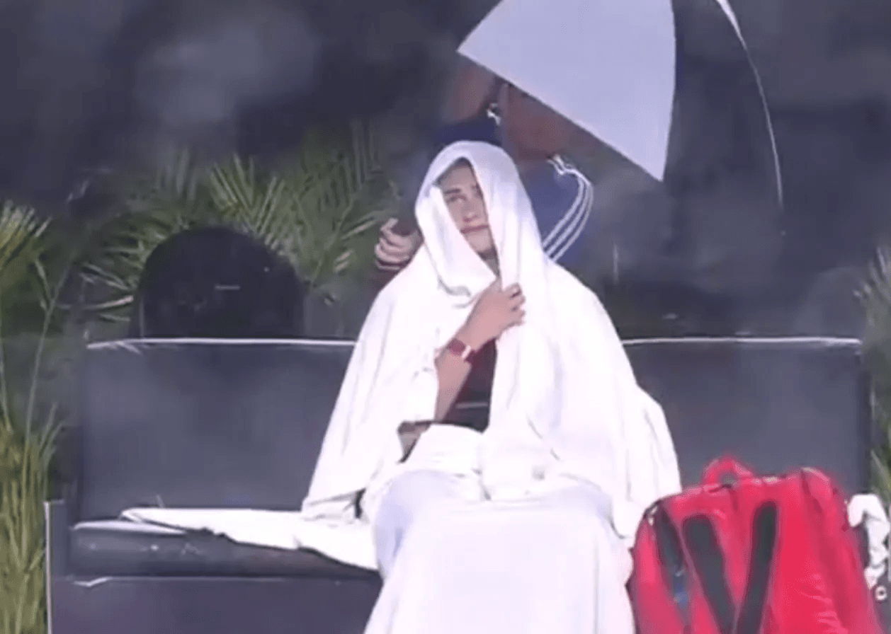 A dismayed Virgin-Mary-esque Aryna Sabalenka sheltering from the wind and the rain at the GNP Seguros WTA Finals Cancun 2023. The paint on the courts had been applied just the week before.