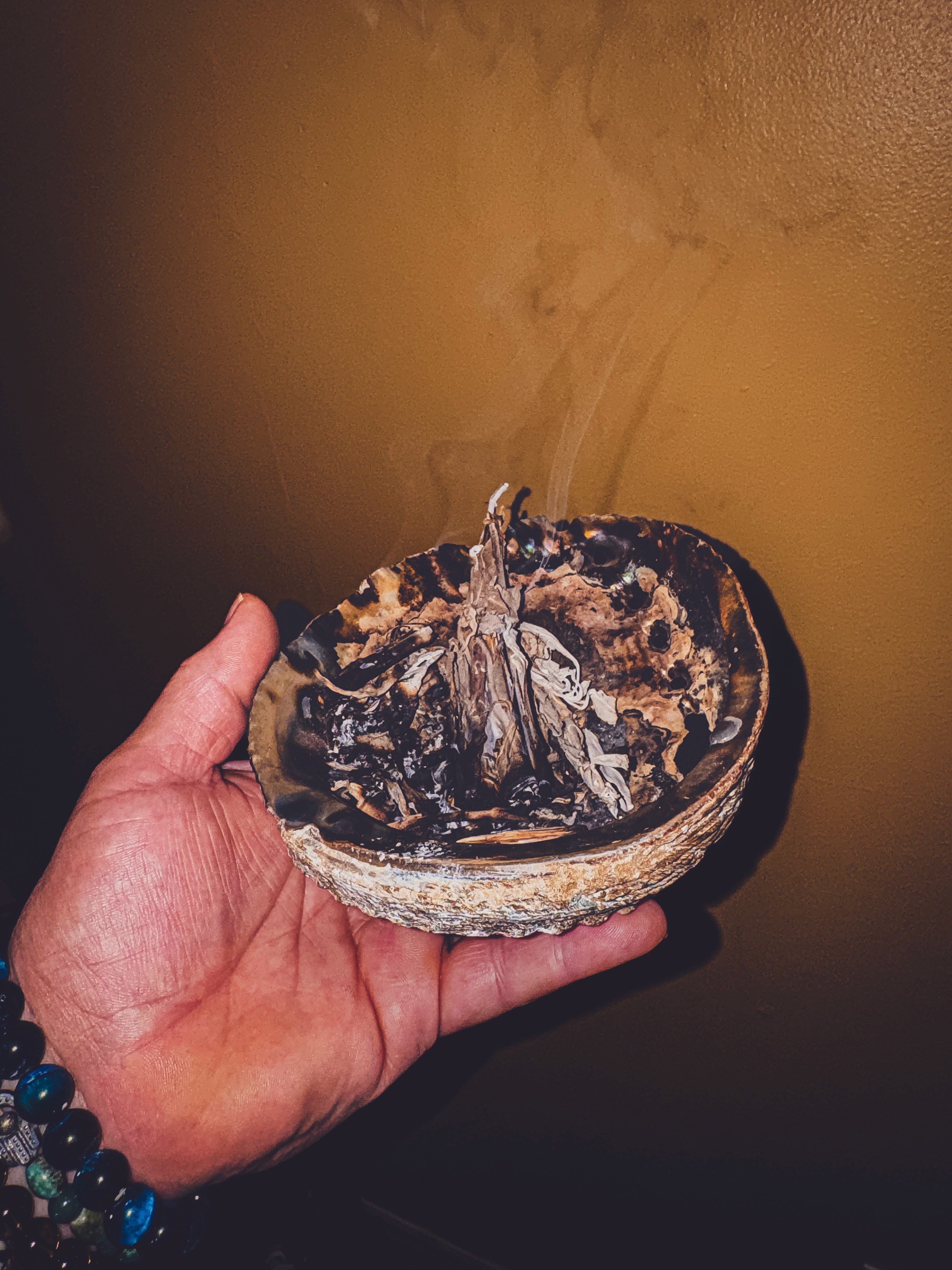 A person with curly hair sits at a desk, working on a laptop in a cozy, well-lit environment.