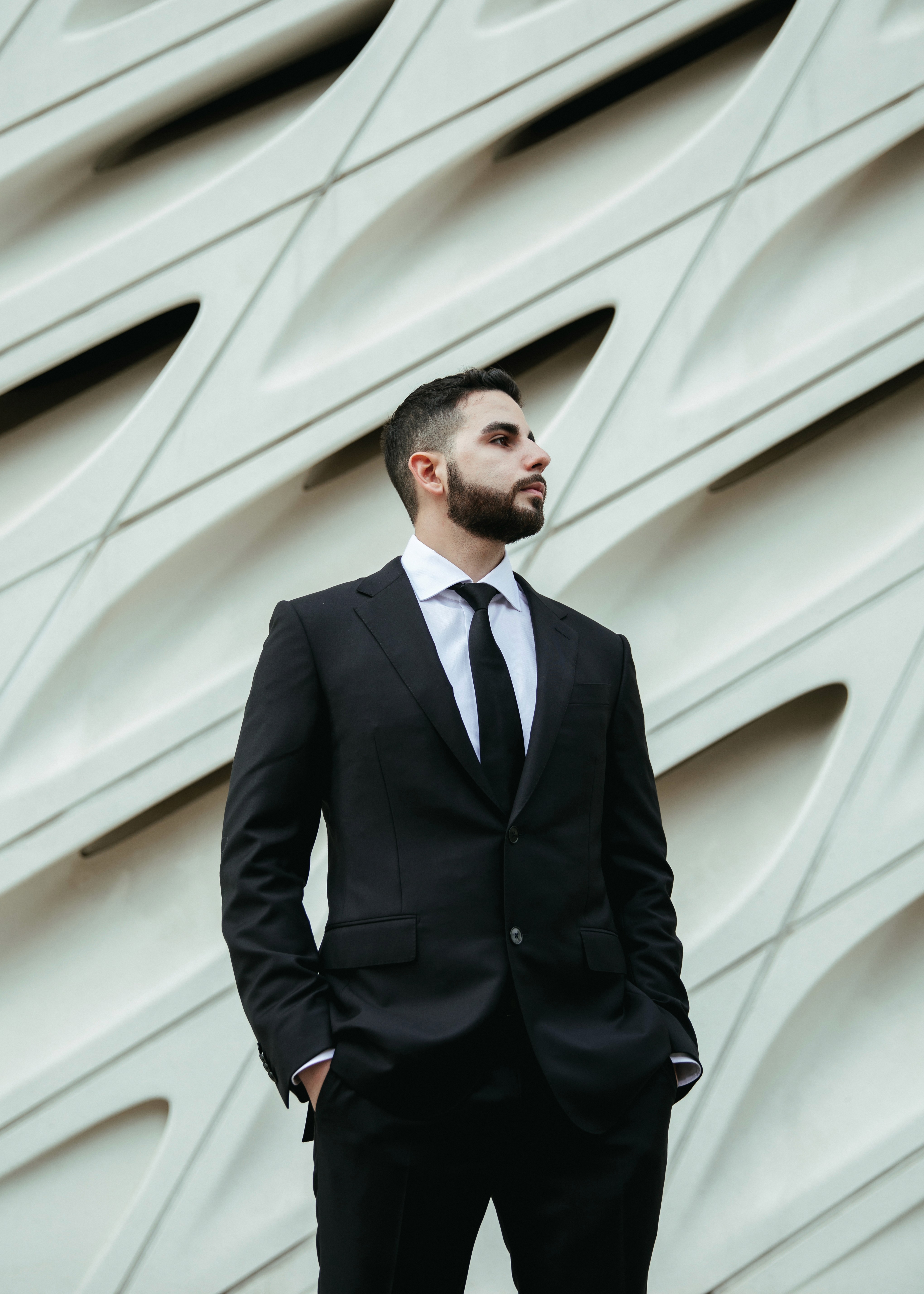 Jon Sargsyan, a personal injury lawyer, at The Injury Law Firm, LLP standing in a suit in front of a building with grooved edges