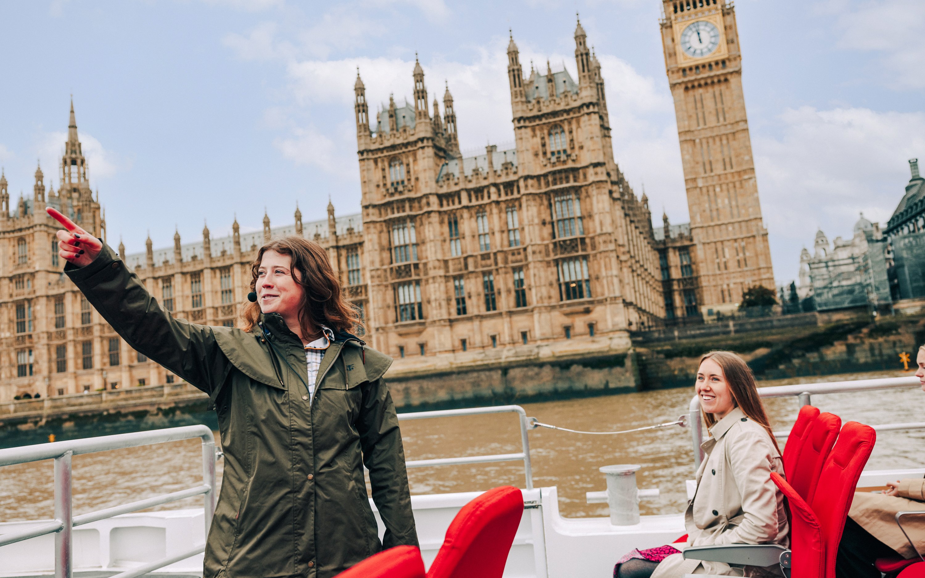 Invitados y guía en el barco del crucero de la Torre de Londres, con las Casas del Parlamento al fondo.
