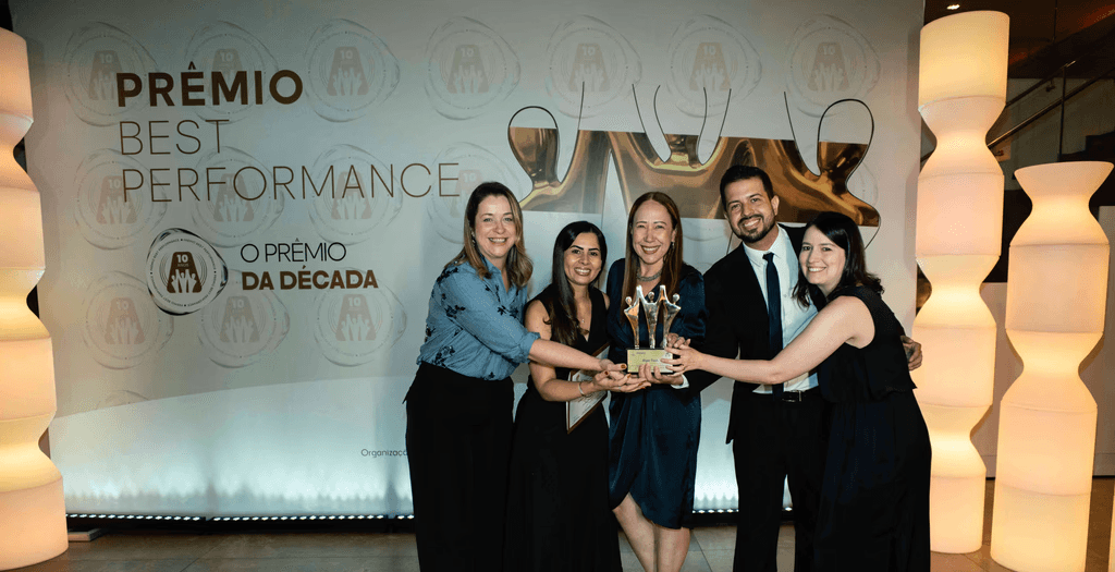 Executivos da Algar Tech posando com troféu ouro e certificado no palco do Prêmio Best Performance 2025