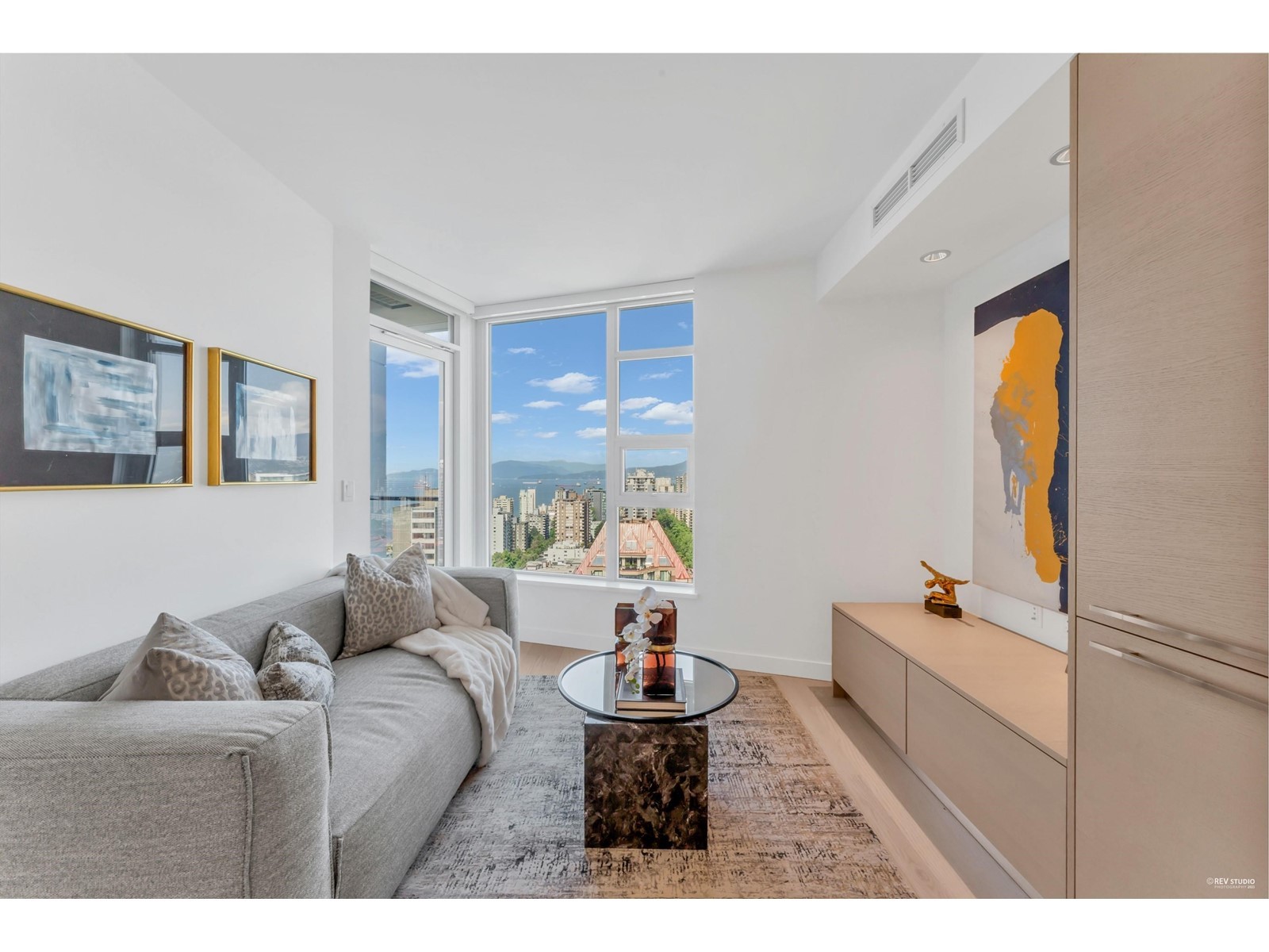 Modern living room with large windows, chic furniture, and a scenic view. Bright and inviting atmosphere.