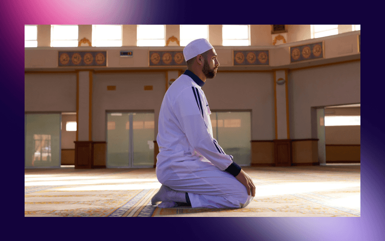 Man in traditional attire standing introspectively in prayer inside a mosque, embodying the virtue of steadfastness in religious practice.