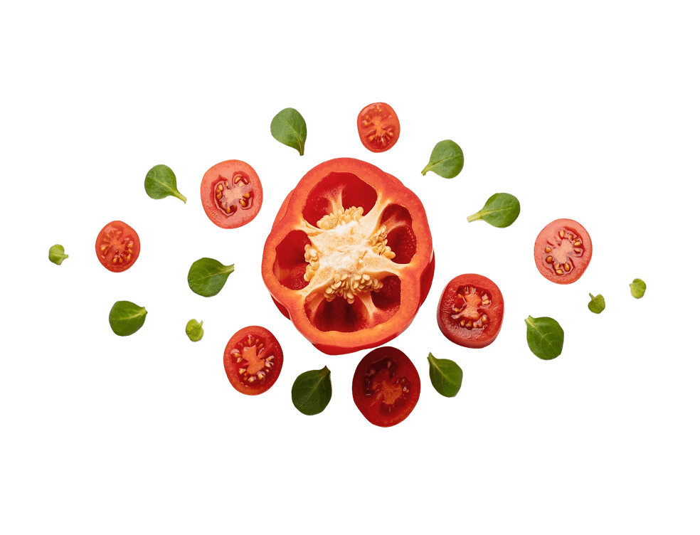 Sliced red bell pepper surrounded by cherry tomato halves and fresh green leaves on a white background.