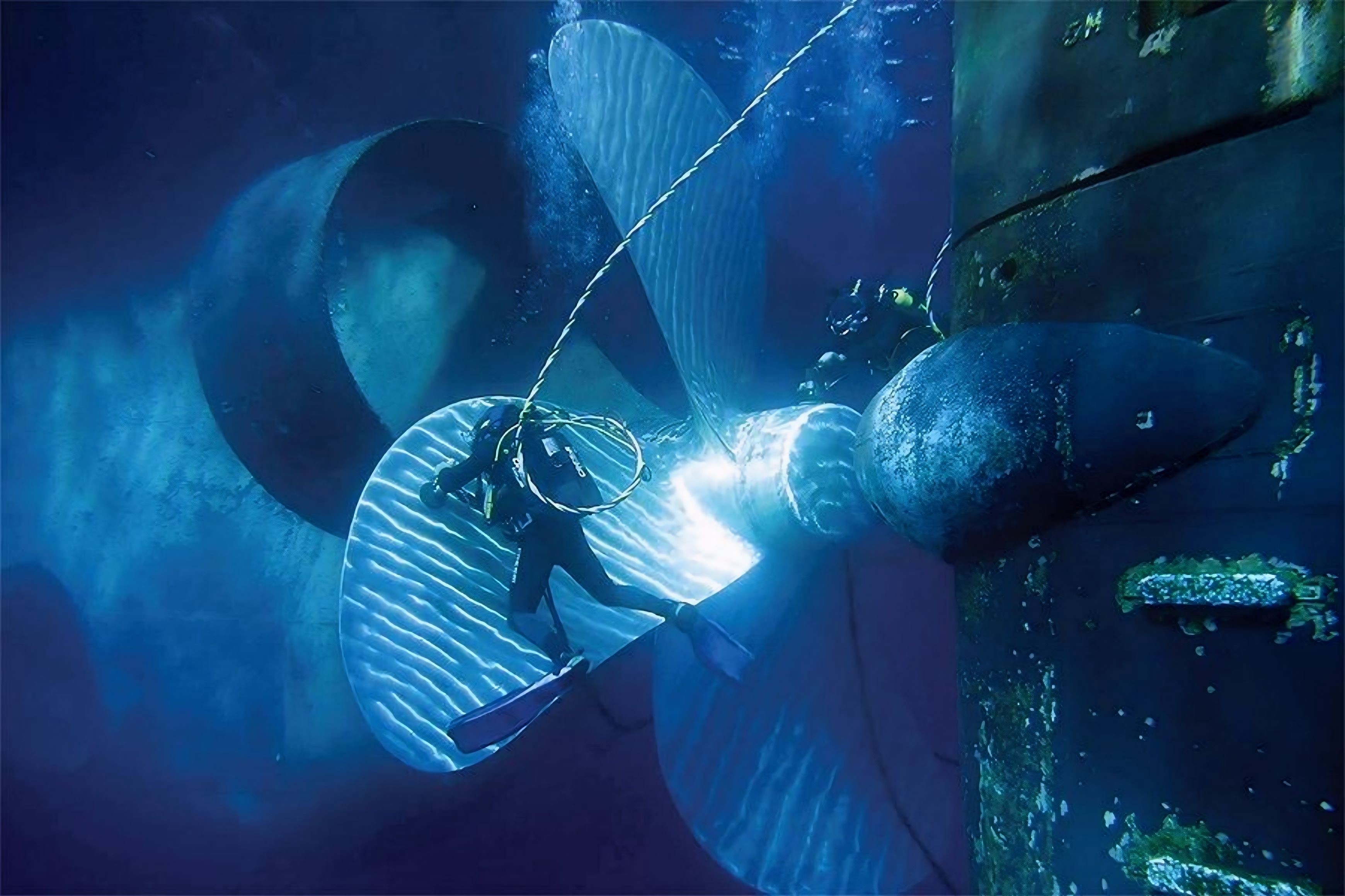 Seachios® Marine Services divers performing underwater propeller polishing and stern area inspection on a large commercial vessel, restoring smooth, mirror-like propeller blades and removing marine growth from the hub and rudder to optimize fuel efficiency, reduce vibration and support class-approved underwater ship maintenance.