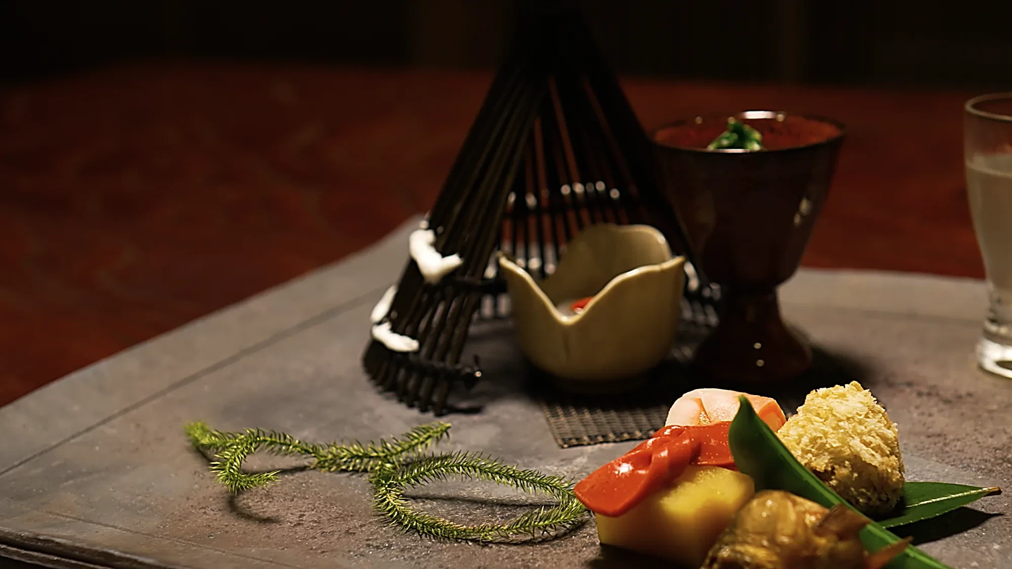 A kaiseki course at Kurokawa Onsen with a bamboo fan garnish and a sake cup