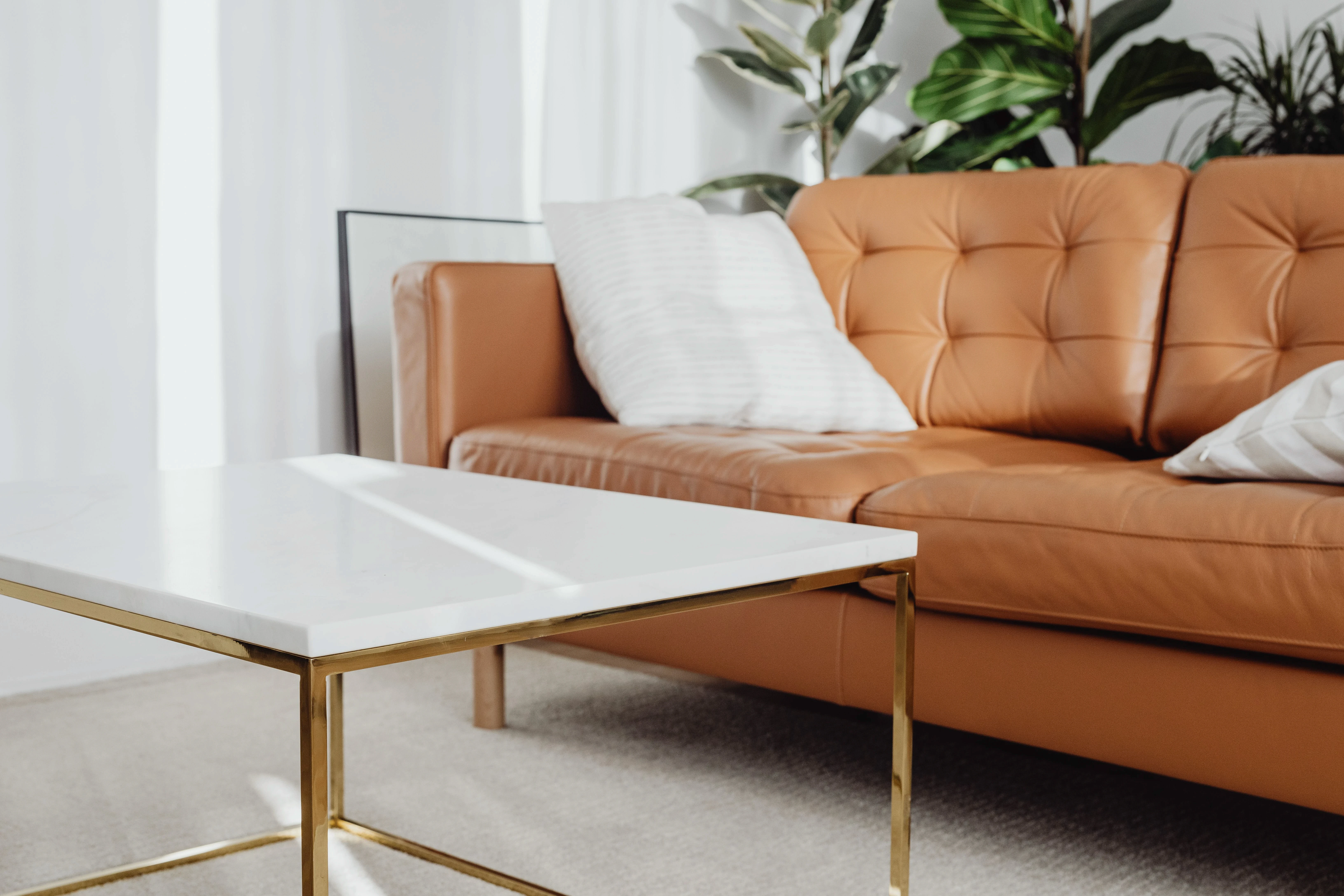 Bright minimalist living room with a white coffee table and wooden furniture accents.