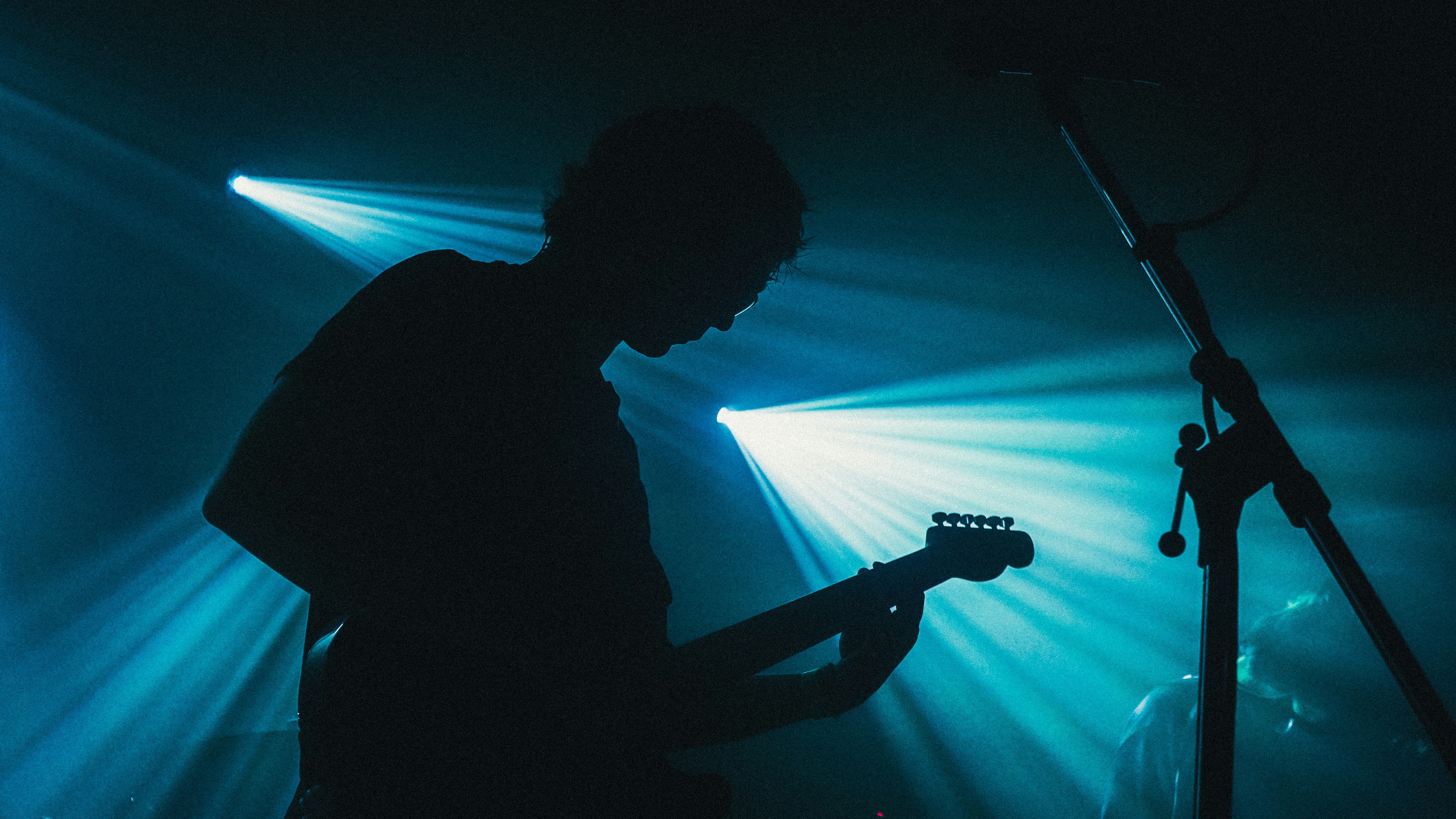 Musician playing guitar on a dimly lit stage.
