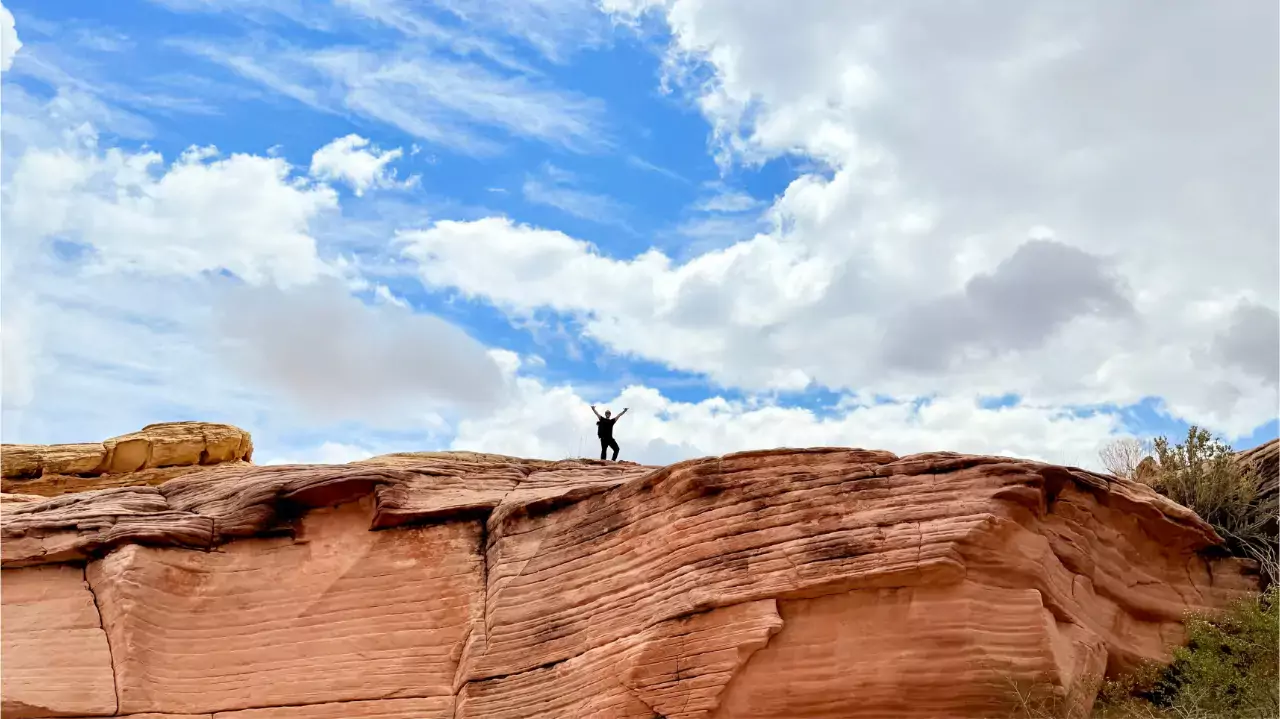 hiker on top of rock formation in the Nevada desert with their arms raised