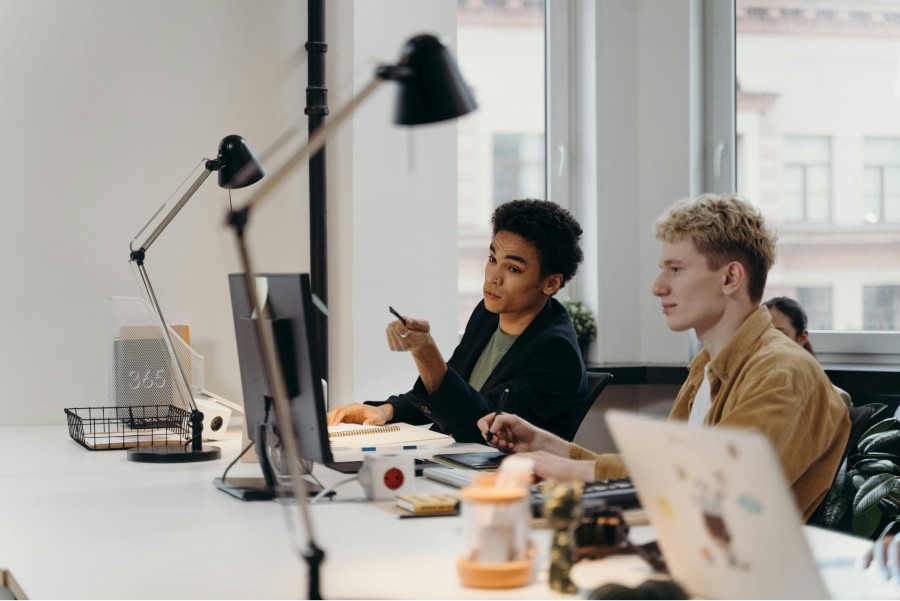 Zwei Kollegen arbeiten gemeinsam am Computer im Büro und besprechen Inhalte am Bildschirm