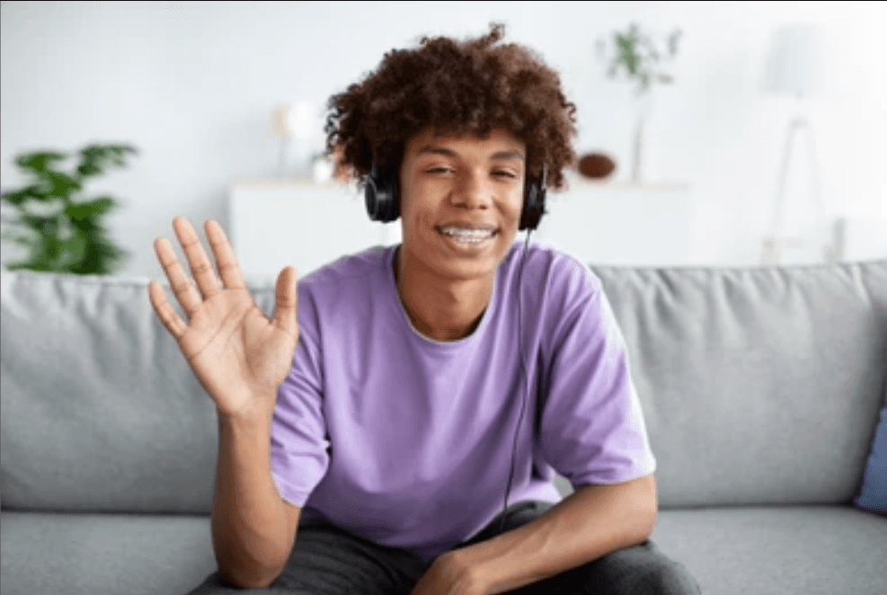 young boy with headphones on and is waving is hand