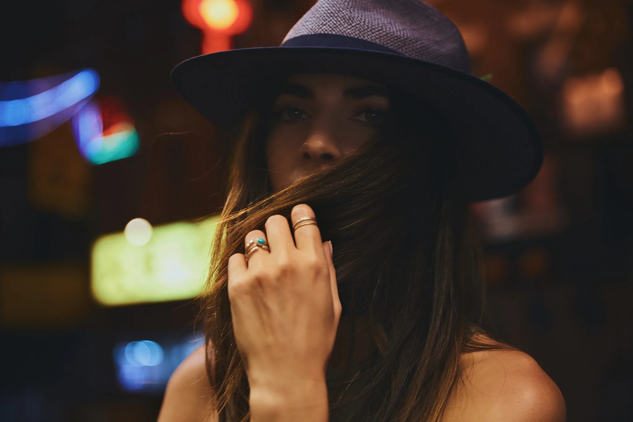 woman pulling hair across face at night — portrait photography by Tom Kubik