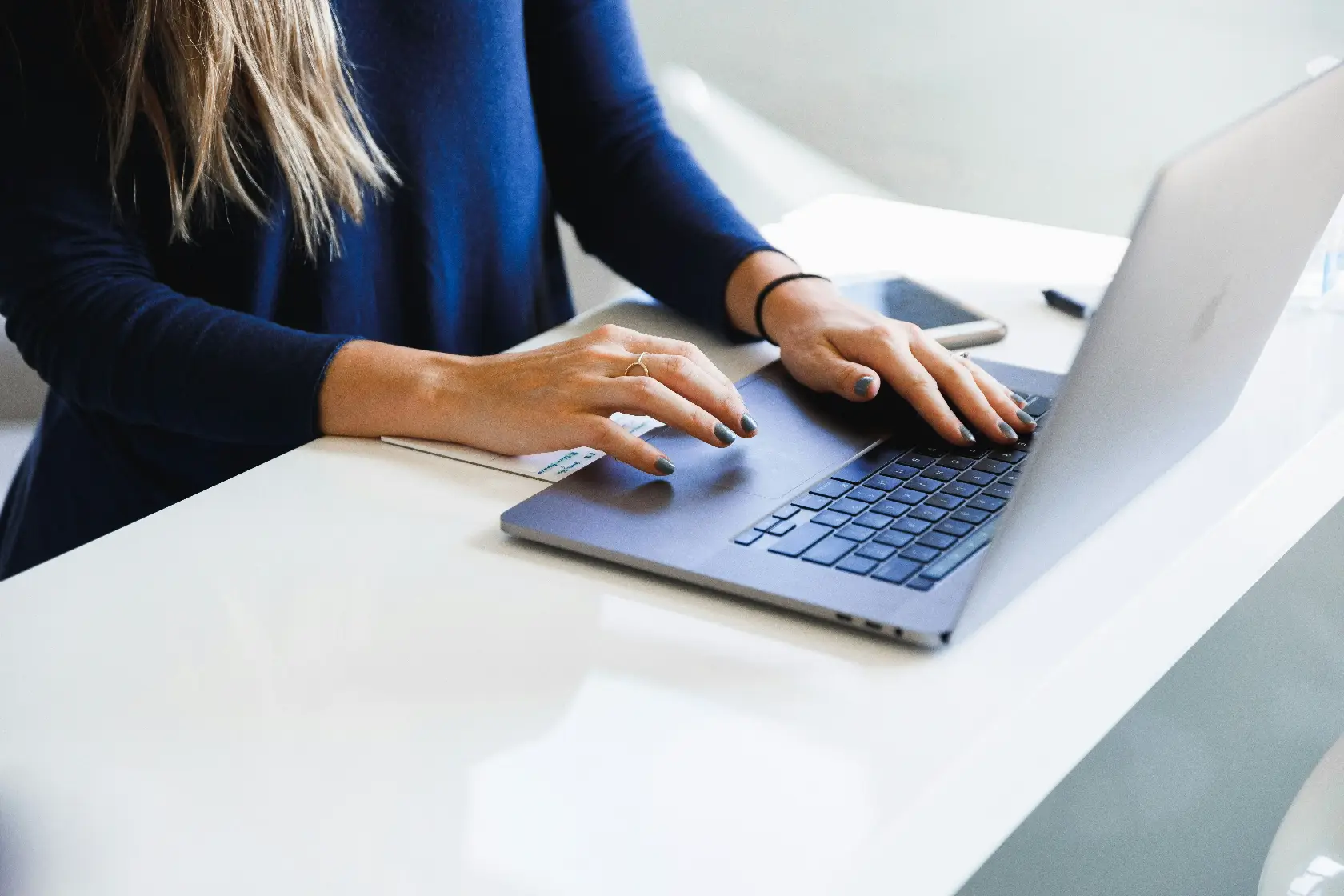 Close up of a person typing on a laptop at a clean desk, suggesting work being done behind the scenes on a real estate listing website. This moment reflects the process of realtor website design, where a professional builds and updates online property listings for clients.