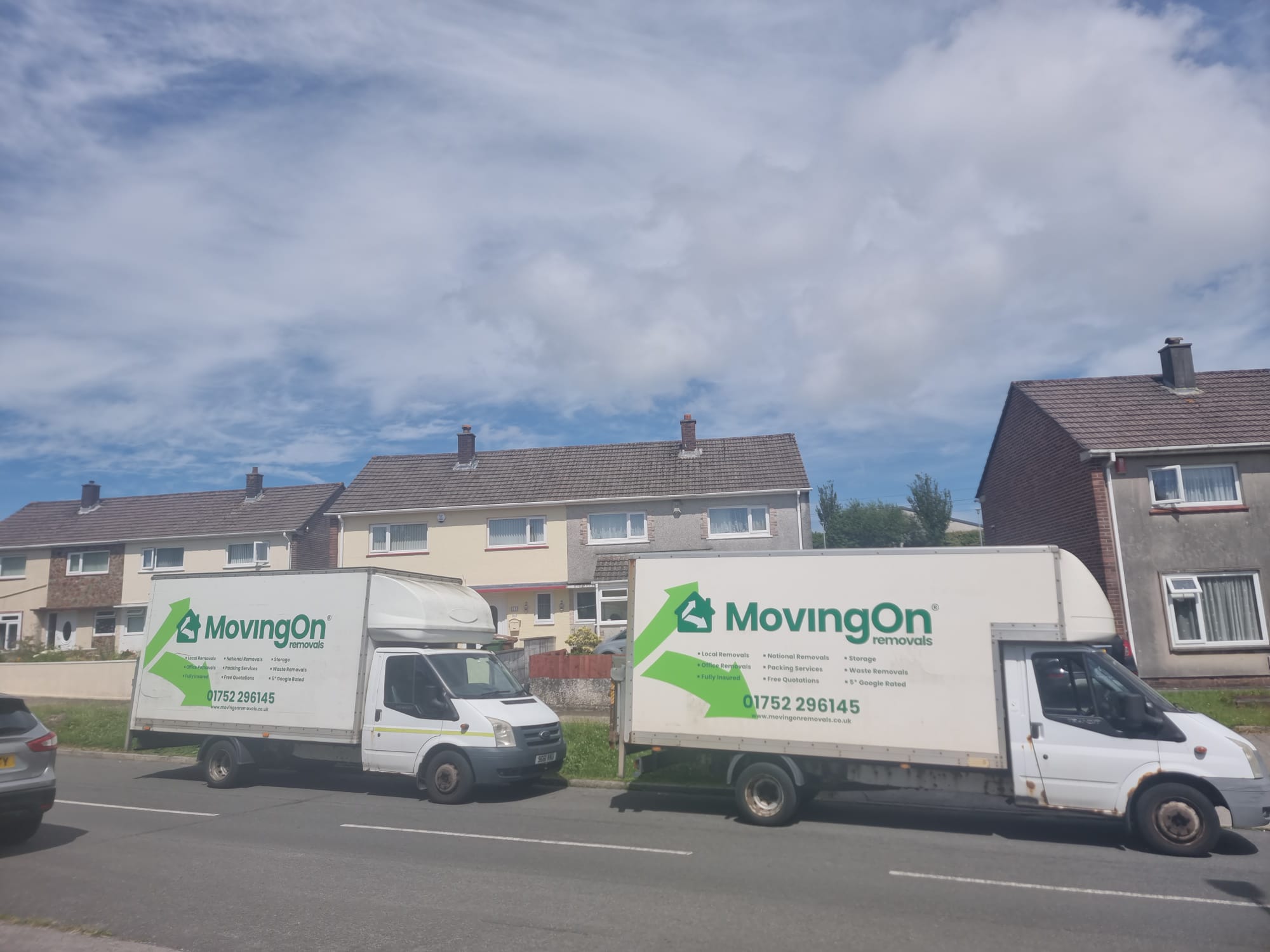 Two branded Moving On Removals Luton vans parked along a residential street in Southway, Plymouth during a local house move.