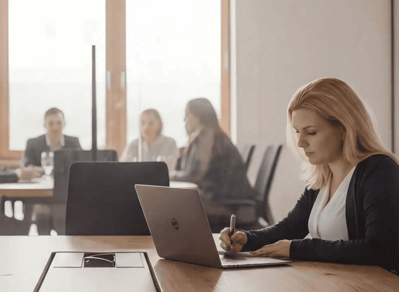 HR-Beraterin am Schreibtisch mit sichtbarem Teammeeting, die Expertise in Employer Branding und Recruiting demonstriert