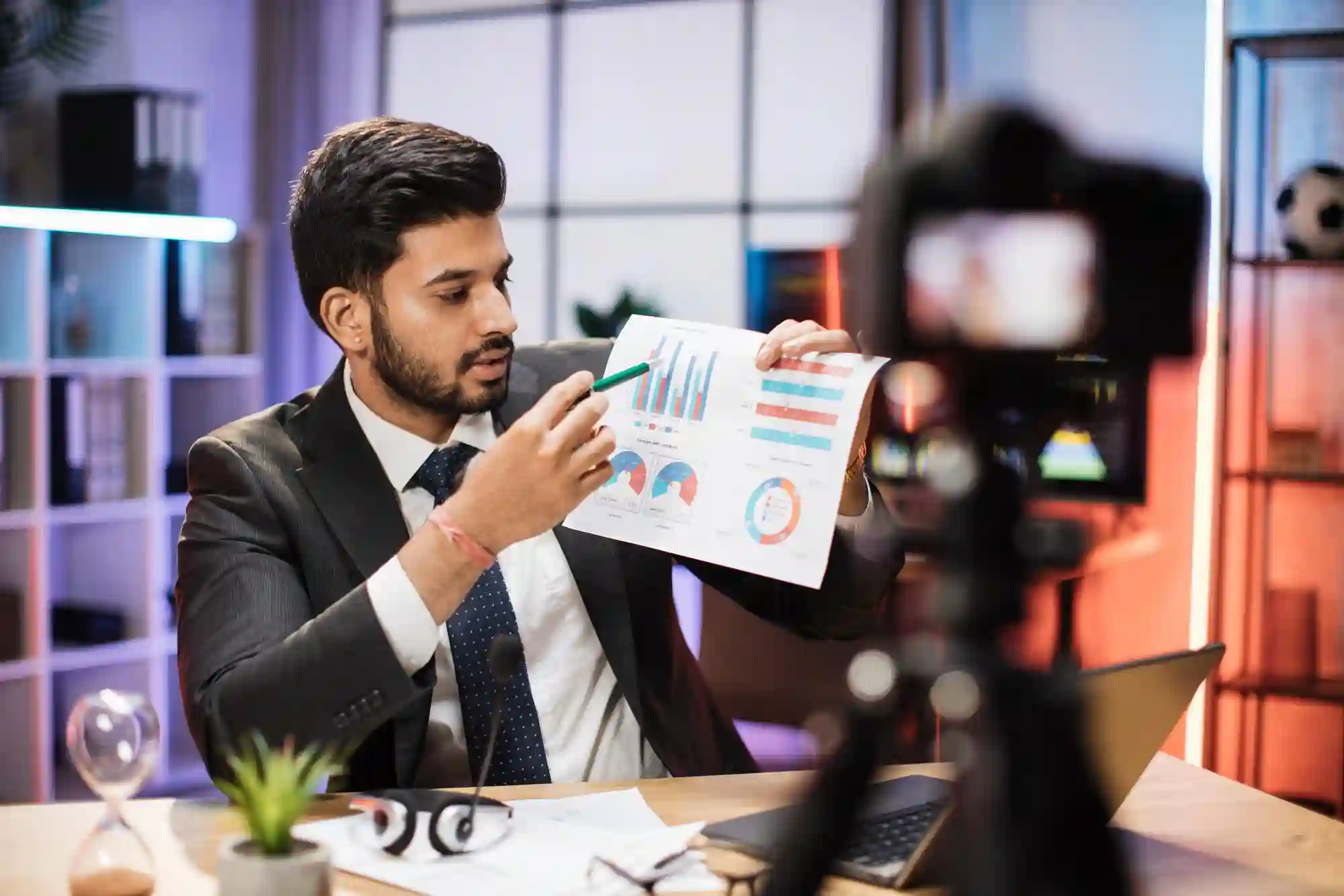 Man in a suit pointing to charts while recording a business-themed TikTok Shop video about data performance.