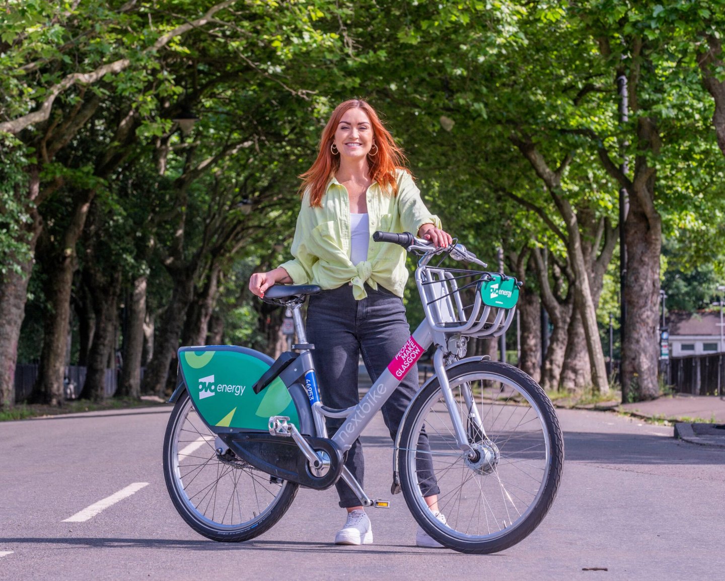 A woman next to an OVO Engergy cycle hire bike