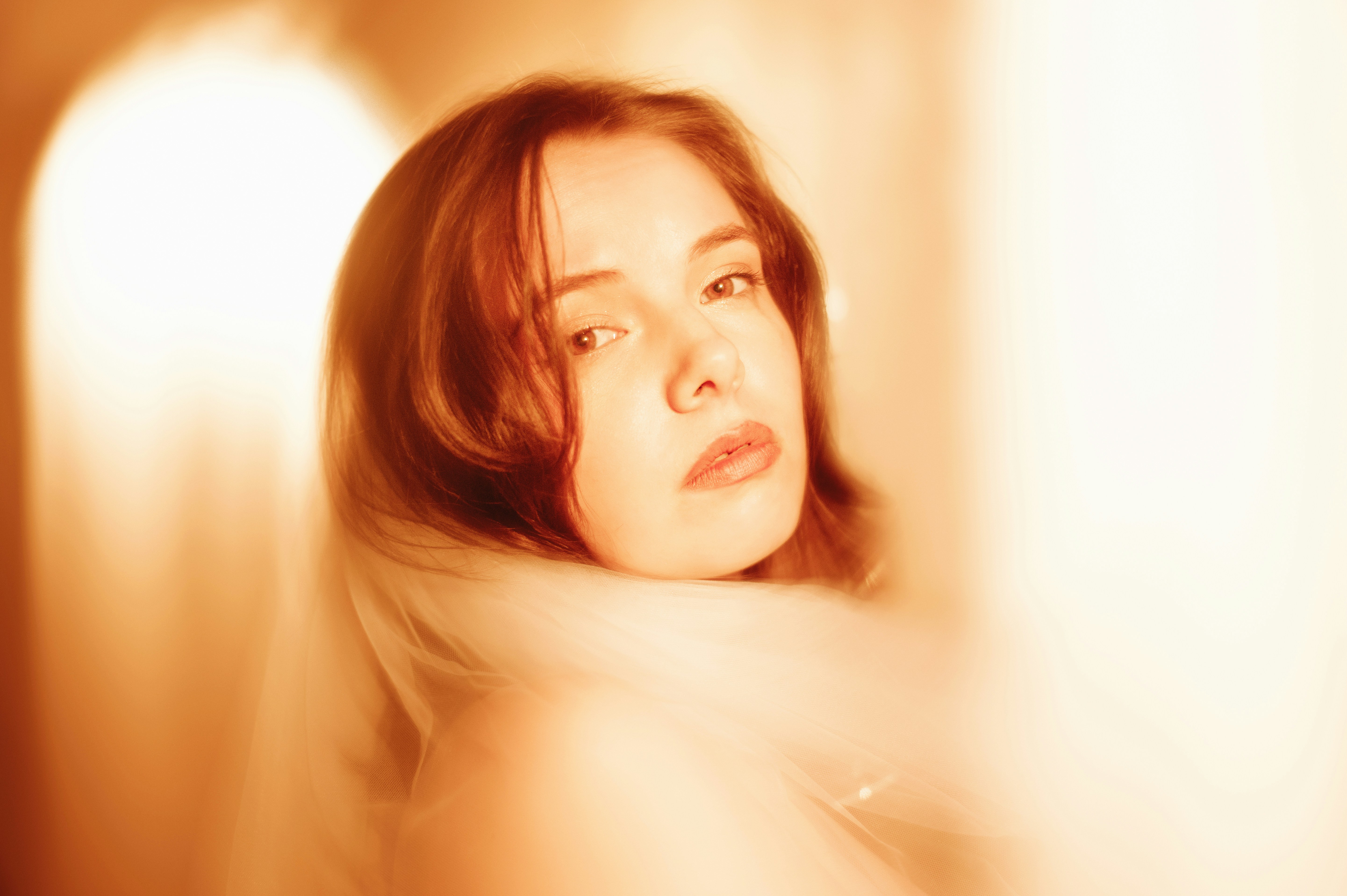 A woman with auburn hair looks over her shoulder.