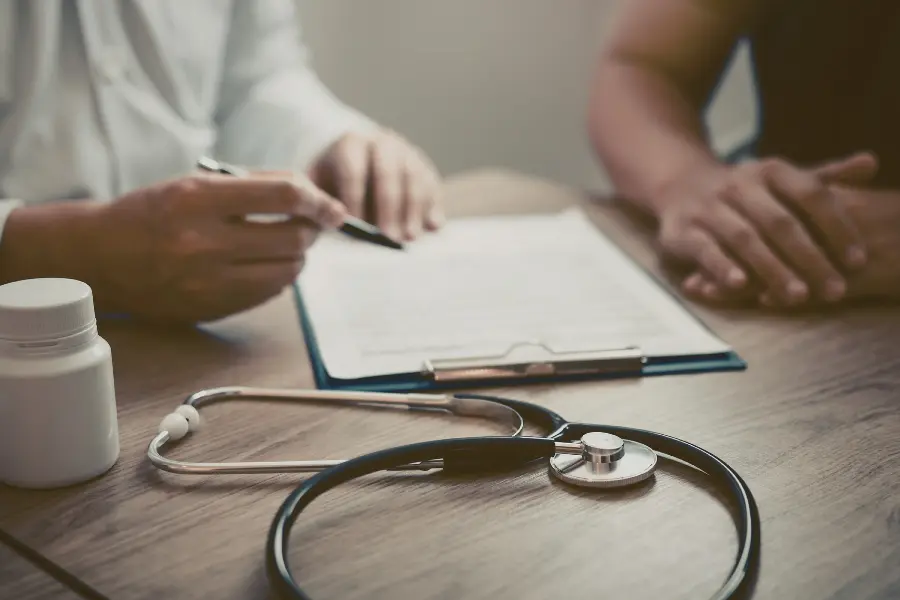 AI in medicine supporting clinical workflows as a doctor points at a laptop screen beside a stethoscope, medications, and syringe.