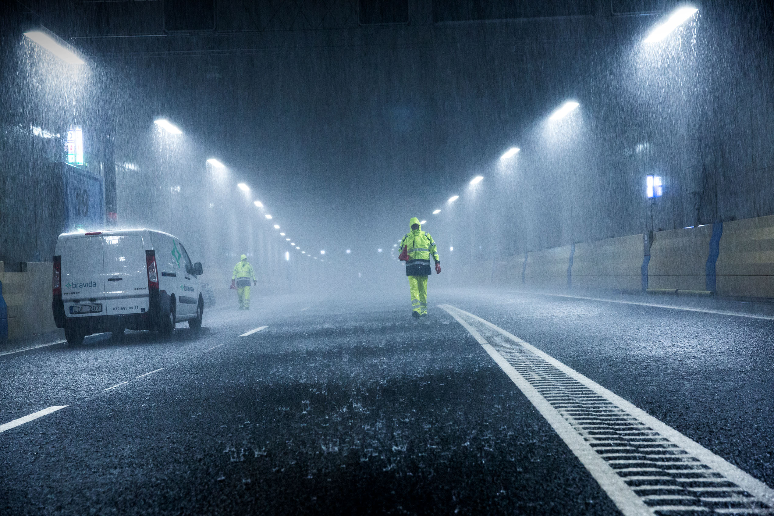 Bravida technicians with white company van in street with heavy rain
