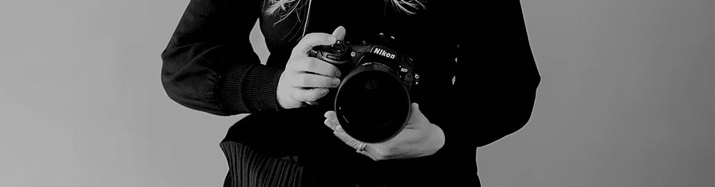 Abstract macro of a glass drop forming a black-and-white flower shape through light refraction on a soft gray background.