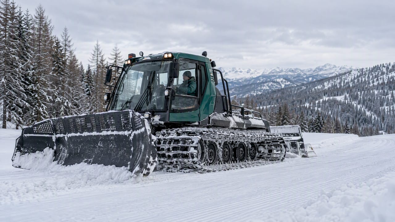 Tracked snowcat travelling across a groomed snow slope in the Western Altai