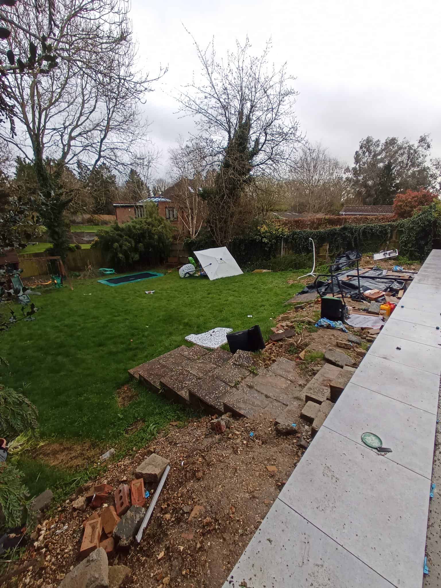 : Garden path through modern black wooden pergolas leading to a green shed.