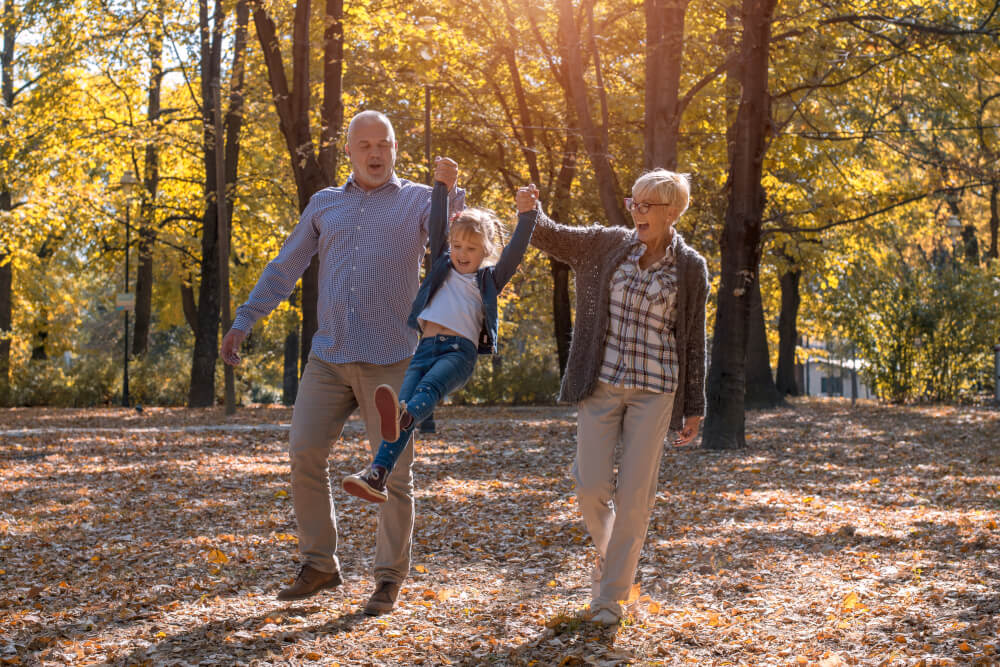 Familie plimbându-se prin parc la apus – liniște și siguranță oferite de asigurarea de viață BIXMA.