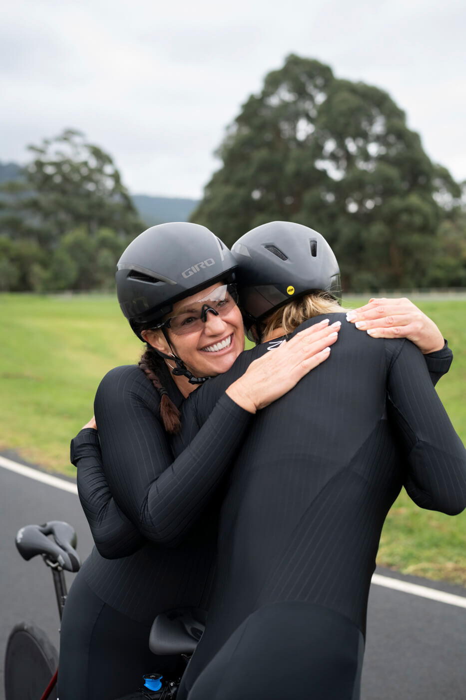 Lily and Jay in their cycling kits, hugging one another